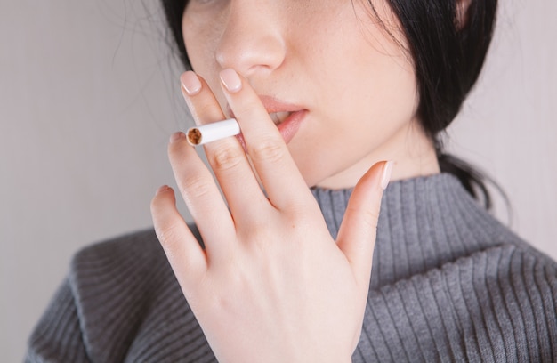 Mulher segurando um cigarro na mão