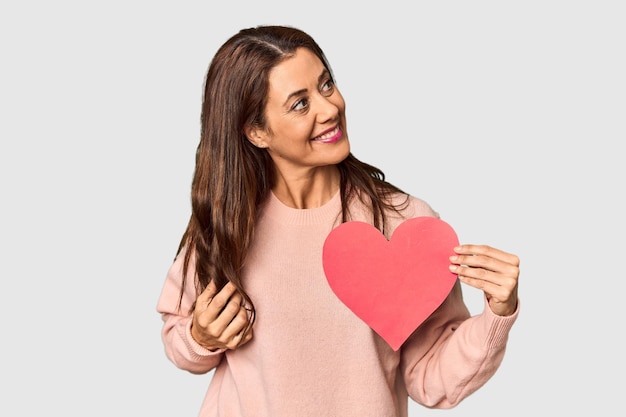 Mulher segurando um coração de papel para valentines no estúdio