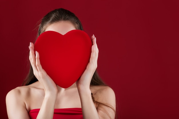 Mulher segurando um coração vermelho sobre fundo vermelho para o dia de são valentim