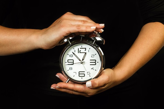 Foto mulher segurando um despertador com as duas mãos