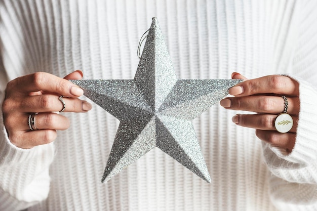 Foto mulher segurando um enfeite de natal com uma estrela de prata brilhante