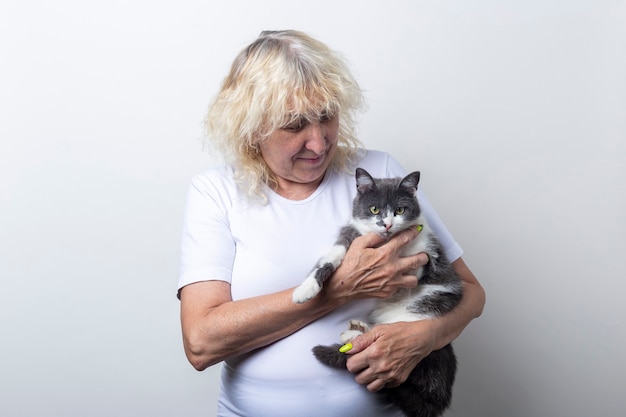 Mulher segurando um gato nos braços sobre um fundo claro.