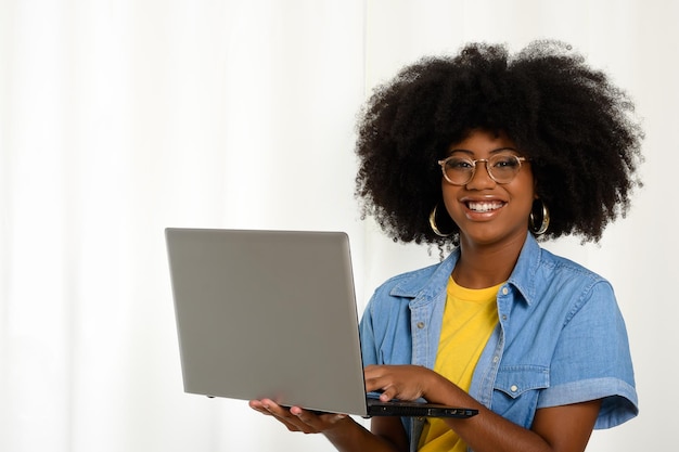 Foto mulher segurando um laptop e digitando no teclado olhando para a câmera mulher preta em backg branco