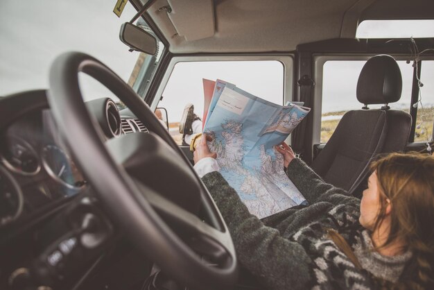 Mulher segurando um mapa deitada no carro