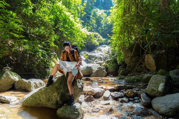 Mulher segurando um mapa enquanto está sentada em uma rocha na floresta