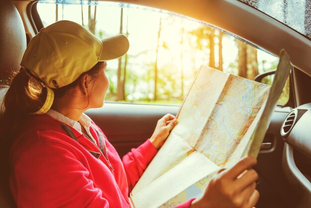 Foto mulher segurando um mapa enquanto está sentada no carro