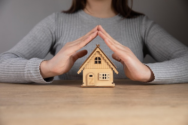 Foto mulher segurando um modelo de uma casa em suas mãos