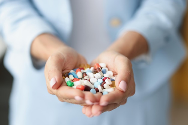 Mulher segurando um monte de medicamentos coloridos na palma da mão para tratamento