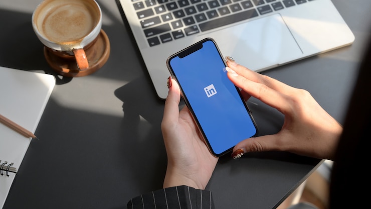 Foto mulher segurando um smartphone com o aplicativo linkedin