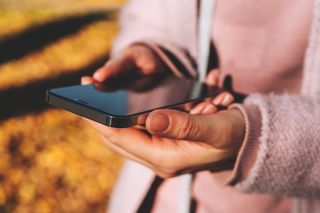 Mulher segurando um smartphone moderno nas mãos e usando redes sociais.