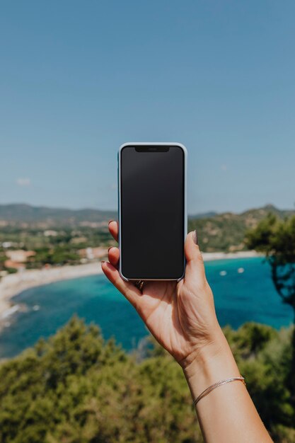 Mulher segurando um telefone na praia