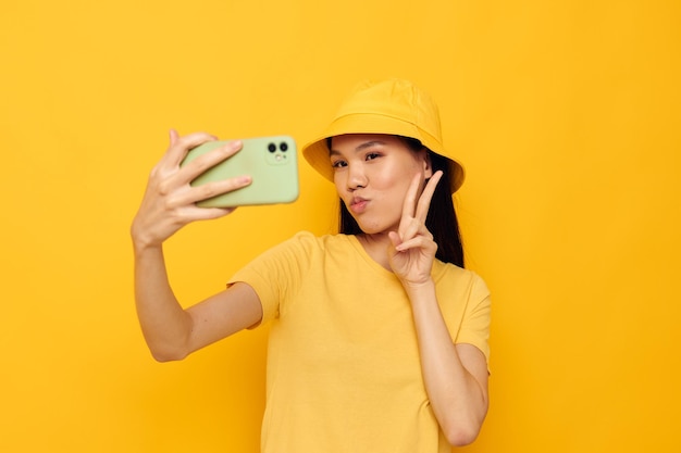 Mulher segurando um telefone posando fundo amarelo de tecnologia de estilo de vida inalterado