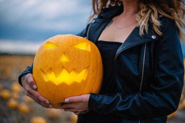 Mulher segurando uma abóbora assustadora de Halloween