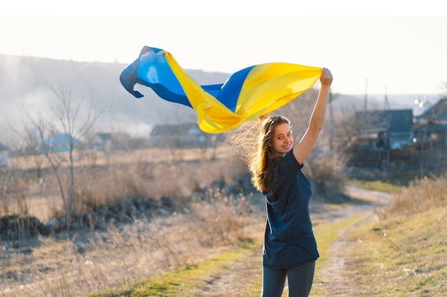 Mulher segurando uma bandeira amarela e azul da ucrânia ao ar livre