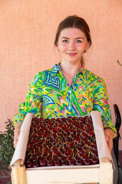 Mulher segurando uma caixa de madeira com cerejas