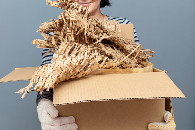 Foto mulher segurando uma caixa de papelão com papel, resíduos de papelão, lixo para reciclagem