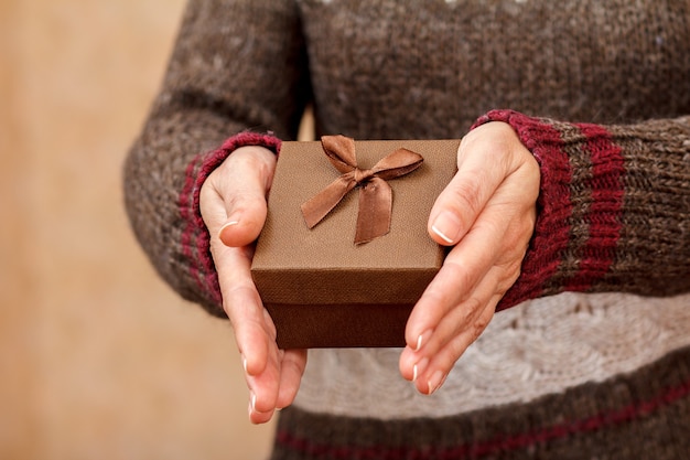 Foto mulher segurando uma caixa de presente nas mãos. profundidade de campo rasa, foco seletivo na caixa. conceito de dar um presente no feriado ou aniversário.