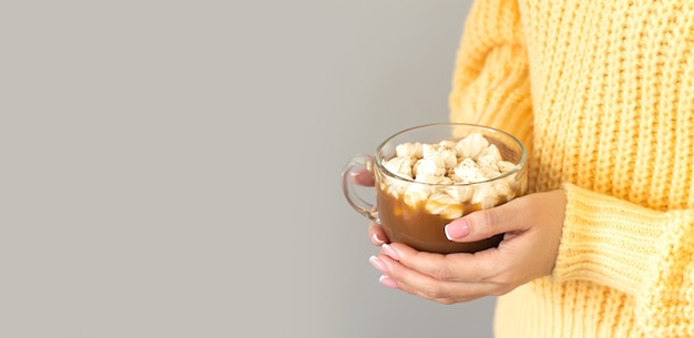 Mulher segurando uma caneca grande de chocolate quente ou chocolate com marshmallow.