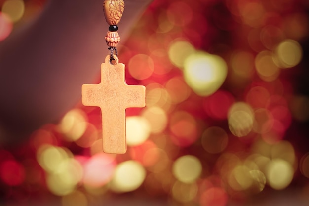Foto mulher segurando uma cruz cristã de madeira sobre um fundo claro bokeh, closeup. espaço para texto.