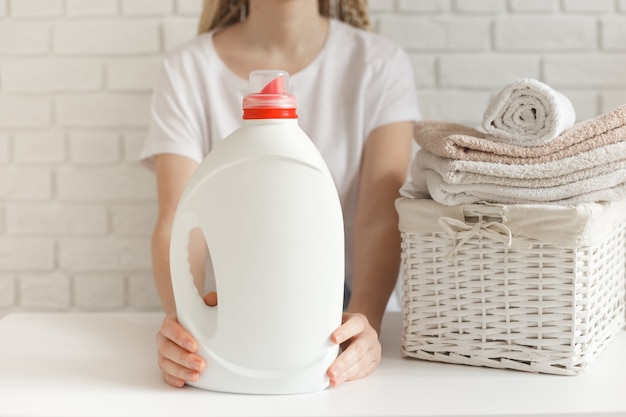 Mulher segurando uma garrafa branca com detergente
