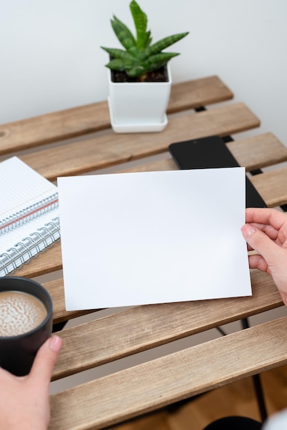 Mulher segurando uma mensagem importante no papel na mesa com café notebooks telefone e planta empresária apresentando informações cruciais na nota senhora mostrando novas idéias no memorando