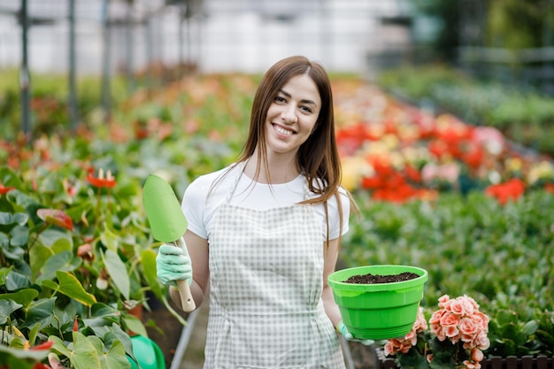 Mulher segurando uma panela e uma pá para transplante de plantas