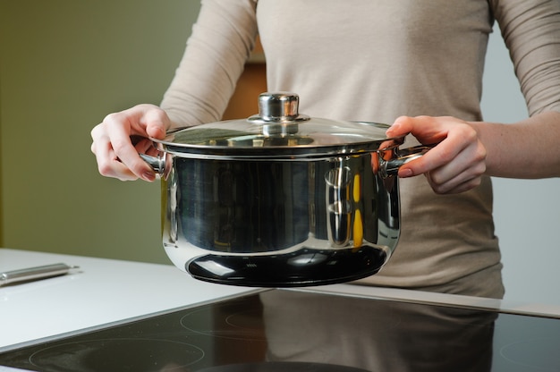 Mulher segurando uma panela em sua cozinha