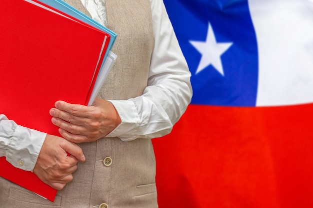 Mulher segurando uma pasta vermelha com a bandeira do chile atrás