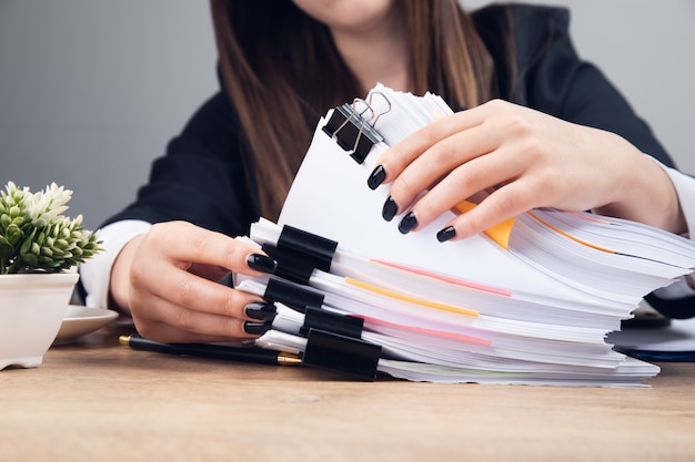 Mulher segurando uma pilha de documentos comerciais na mesa