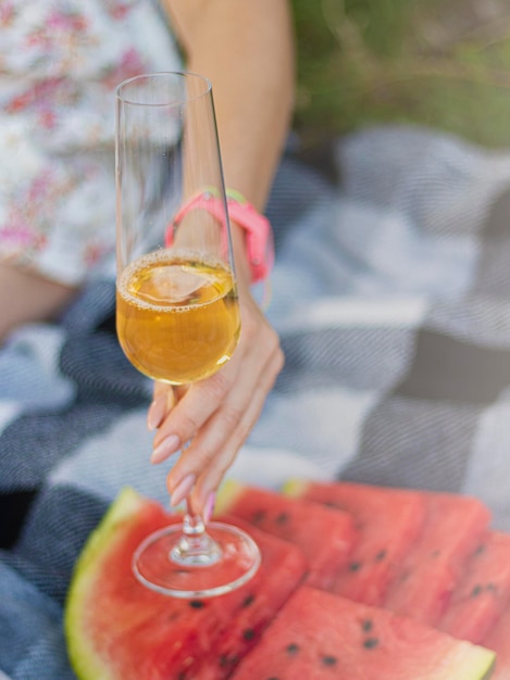 mulher segurando uma taça de champanhe Piquenique de verão ao ar livre com cobertor estilo ecológico com frutas