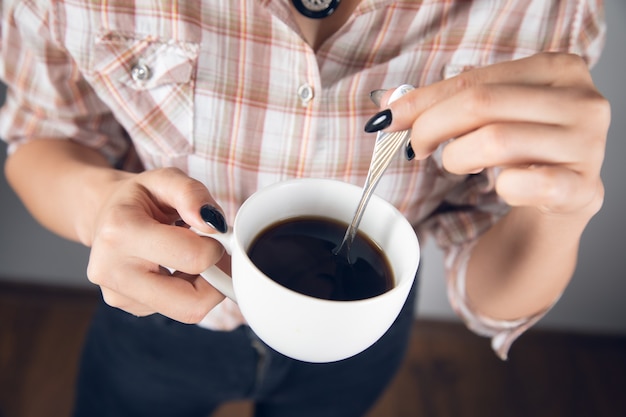 Mulher segurando uma xícara de café com uma colher