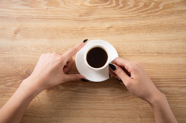 Mulher segurando uma xícara de café na mesa