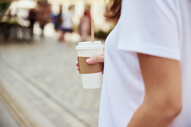 Mulher segurando xícara de café de papel na rua da cidade