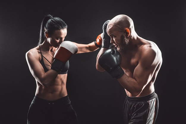 Foto mulher sem camisa, exercitando-se com o treinador na aula de boxe e defesa pessoal luta feminina e masculina