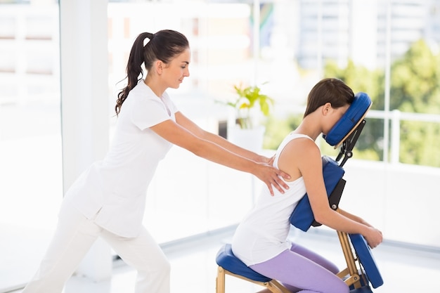 Mulher sendo massageada na cadeira por massagista