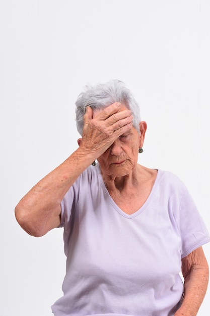 Mulher sênior com dor de cabeça no fundo branco