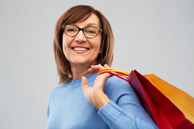 mulher sênior com sacos de compras sobre cinza