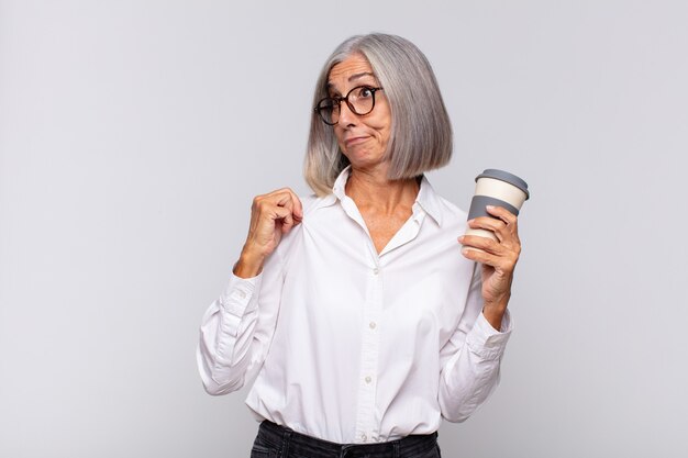 mulher sênior com um café para viagem