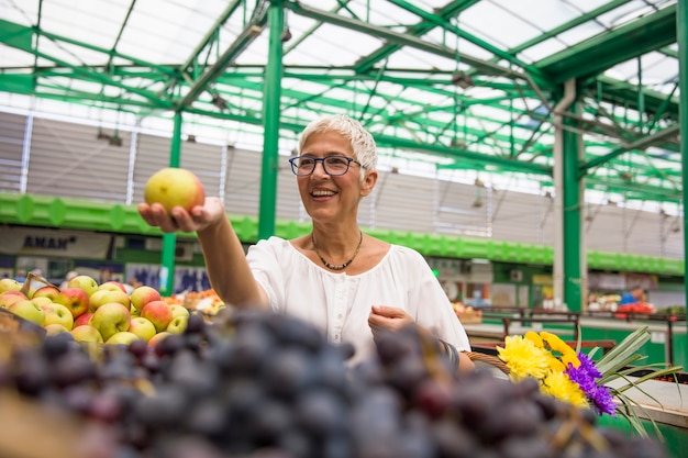 Mulher sênior, comprando maçãs, em, mercado