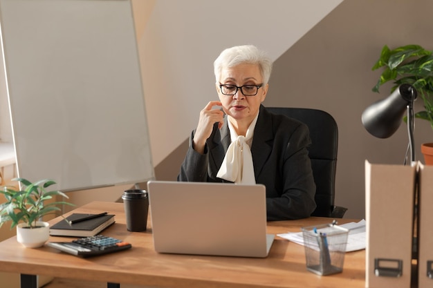 Mulher sênior confiante e elegante de meia-idade usando laptop no local de trabalho elegante e madura s