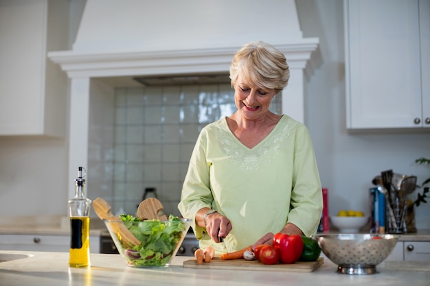 Mulher sênior cortar legumes para salada