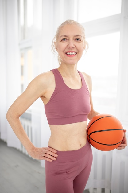 Mulher sênior de tiro médio segurando uma bola