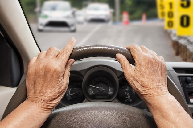 Mulher sênior dirigindo um carro na estrada de construção.