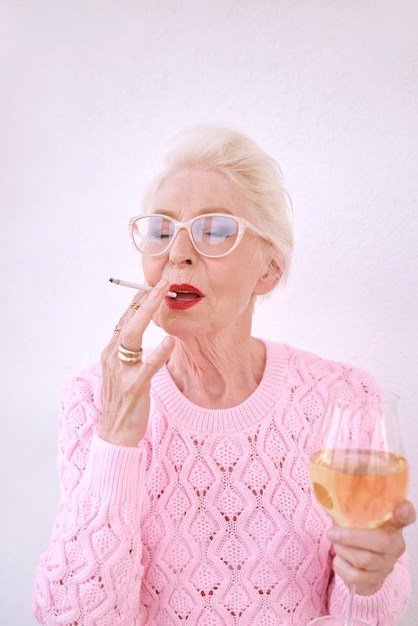 mulher sênior elegante fumando cigarro com uma taça de vinho branco