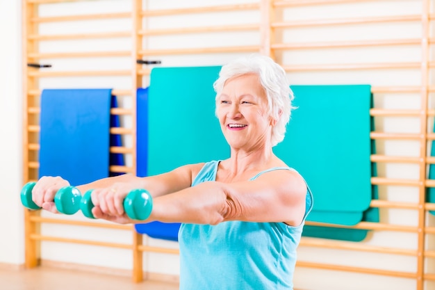 Mulher sênior fazendo esporte fitness na academia com halteres