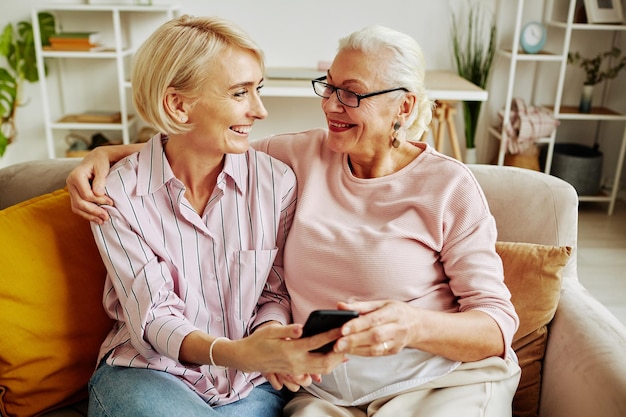 Mulher sênior feliz com filha adulta usando smartphone