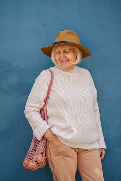 mulher sênior feliz com saco de pano. idosa alegre carregando um saco de tecido com a mercearia