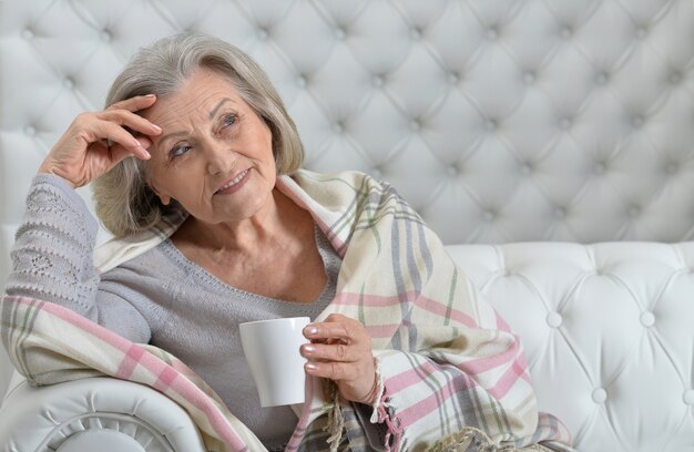 Mulher sênior feliz descansando em casa com uma xícara de chá