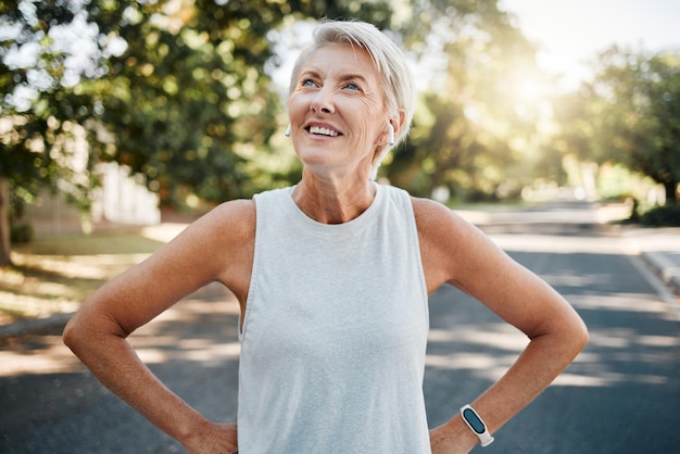 Mulher sênior fitness com fones de ouvido e smartwatch para seu exercício ao ar livre ouvindo música ou podcast de motivação com tecnologia 5g Pessoa idosa saudável ou corredor feliz com os resultados do treino