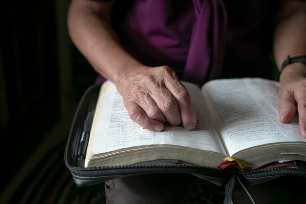 Mulher sênior lendo com as mãos em um livro aberto